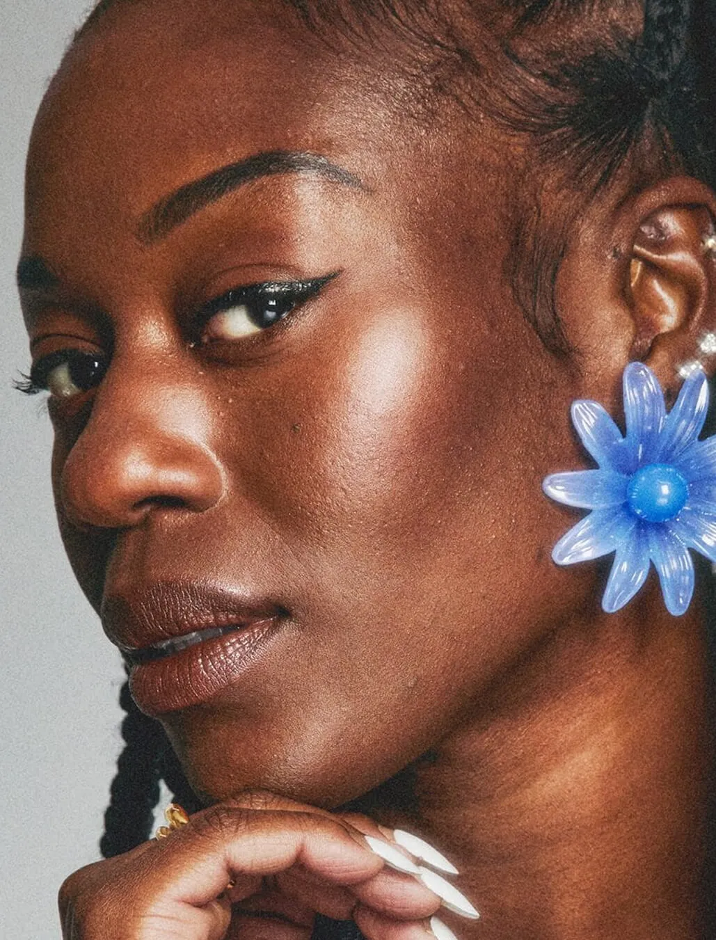 Close-up portrait of a woman with winged eyeliner and a blue flower earring